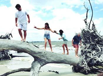 Family of four playing on a fallen tree trunk