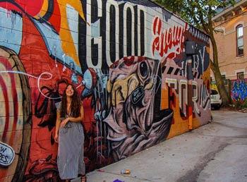 Girl in a long dress standing in front of a boldly colored mural