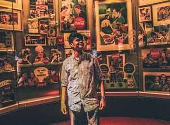 A man standing in front of a wall of frames with old fashioned advertisments
